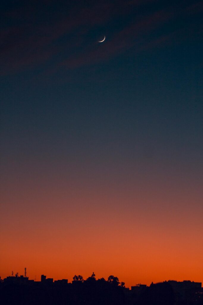 Crescent moon and fiery orange sunset horizon